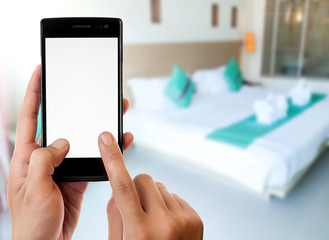 Man's hand holding mobile smartphone,Hotel room background