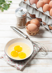 Eggs and whisk on wooden table