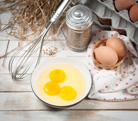 Eggs and whisk on wooden table