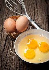 Eggs and whisk on wooden table