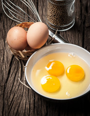 Eggs and whisk on wooden table