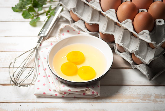 Eggs and whisk on wooden table