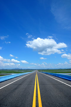 Empty road and the yellow traffic lines with blue sky.