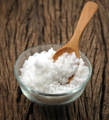 white salt in wooden spoon on wood