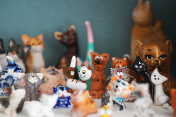 A collection of figurines of cats and cats from different countries and cities on the shelf. The cats brought from travel