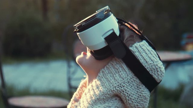 A cute little girl uses a virtual reality VR helmet with pleasure. She very impressed