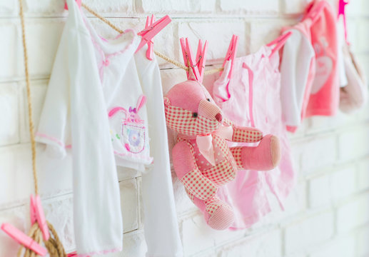 Baby clothes and bear toy hanging on the wall as decoration side view