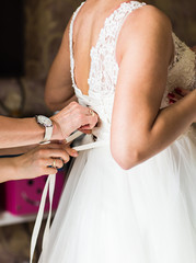 Obraz na płótnie Canvas Bridesmaid is helping the bride to dress