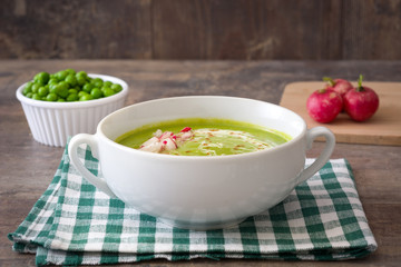 Peas cream with radishes on rustic wood
