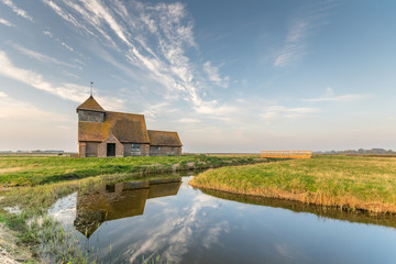 Thomas Becket church, Fairfield, Romney Marsh reflected in river water.