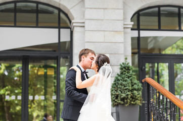 Fototapeta premium Handsome brunette groom kissing beautiful bride in wedding dress 