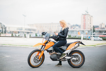 Fototapeta na wymiar Young woman at motorcycle using mobile phone