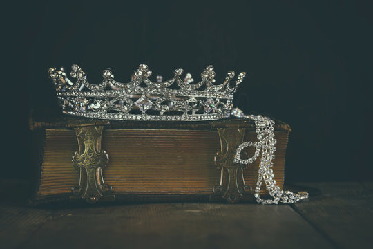 low key image of beautiful diamond queen crown on old book