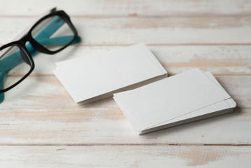 Fototapeta na wymiar blank business cards and eyeglasses on wooden table