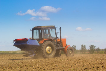 Obraz premium Tractor Spaying a field in the spring accompanied