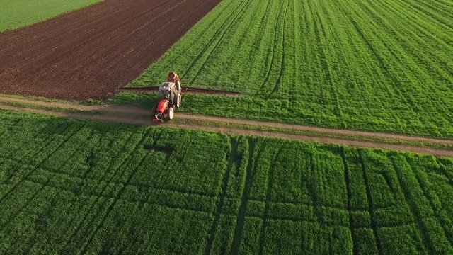 Aerial view of tractor spraying wheat field