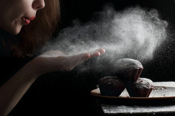 Blowing powdered sugar with hands on the muffins