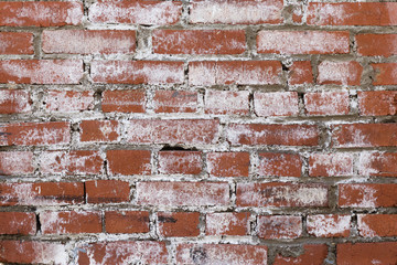red brick wall with cracks covered with white paint