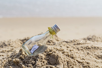 SOS message in glass bottle on the beach.