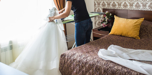 Housewife ironing wedding dress in living room