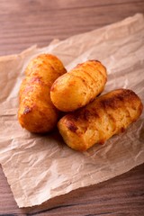 Three crispy potato croquettes on piece of brown paper