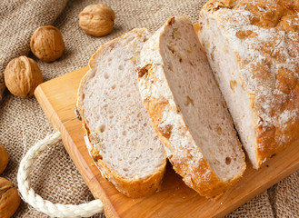 Freshly healthy home bread with walnut on wooden board and burlap in rustic style.