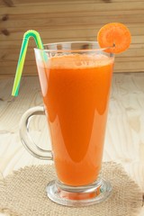 Glass of carrot juice and carrots on the wooden table. Healthy juice full of vitamins and fiber. Diet Food. Carrot segments on a wooden background.
