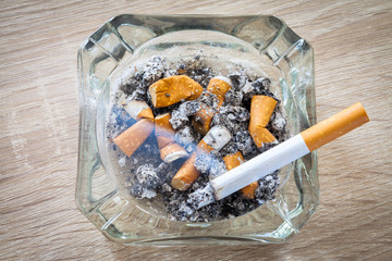 rauchende Zigarette in einem vollen Aschenbecher