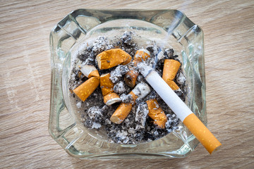 rauchende Zigarette in einem vollen Aschenbecher
