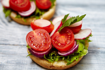 Healthy food concept. Tasty homemade sandwiches with tomato, onion, radishes, parsley, on a wooden gray board