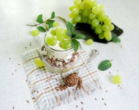 Healthy breakfast -   rice with yogurt, flax seeds and grapes.