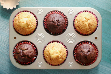 Homemade muffins in a baking trayon a wooden background. Top view
