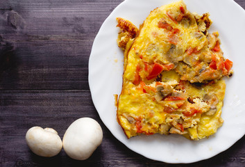 a piece of omelet on a white plate and two mushroom. Top view. Blank space