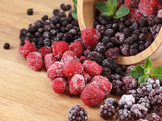 Frozen berries on a wooden table, covered with ice