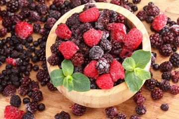 Frozen berries in wooden bowl, covered with ice
