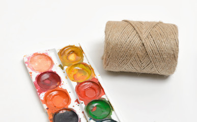 Top view of the composition with used watercolor paints and filament twine in coils isolated on a...