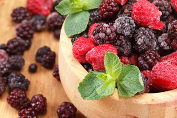 Frozen berries in wooden bowl, covered with ice