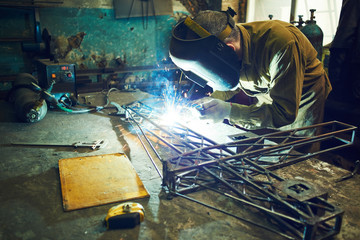 The wizard removes the excess weld using a power saw with a metal layout of a construction crane