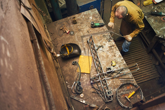 The wizard removes the excess weld using a power saw with a metal layout of a construction crane