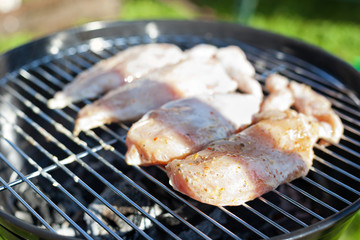 Raw chicken fillet breast cooking on barbeque grid