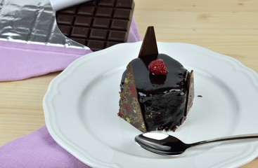 Delicious chocolate cake on white porcelain plate with one bite in spoon and bars of just opened...
