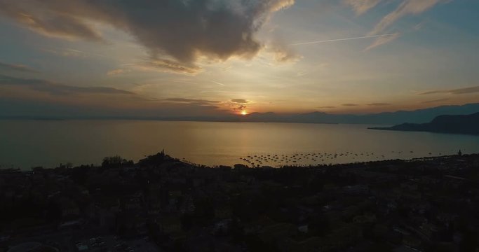 Wonderful panoramic view on sunset over beautiful lake Garda (Lago di Garda) with mountains, yachts and sailingboats in Bardolino harbor (Verona, Italy). Aerial view
