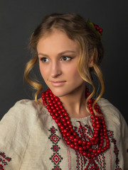 Beautiful happy cute young woman in Ukrainian embroidery on a gray background