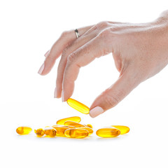 Soft gels pills with Omega-3 oil in fingers closeup on white