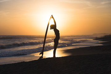 Beautiful young surfer girl in bikini with surfboard on a beach