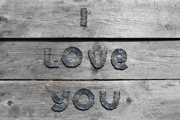 Text I LOVE YOU written by metal nails on wooden background