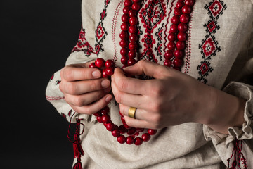 Red beads in hands. Ukrainian embroidery. Rosaries.