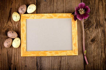 Fototapeta na wymiar Vintage Easter background with picture frame on dark wooden board with copy space.