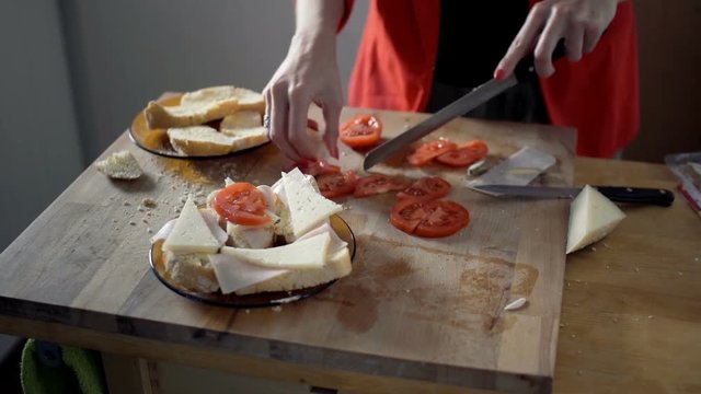 Female hands preparing sandwich for breakfast on wooden table
