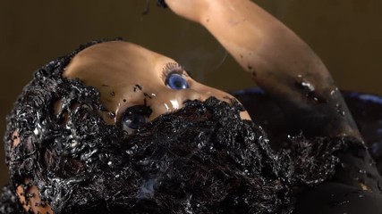 Child's baby doll burnt in a home fire with smoke coming from charred plastic.